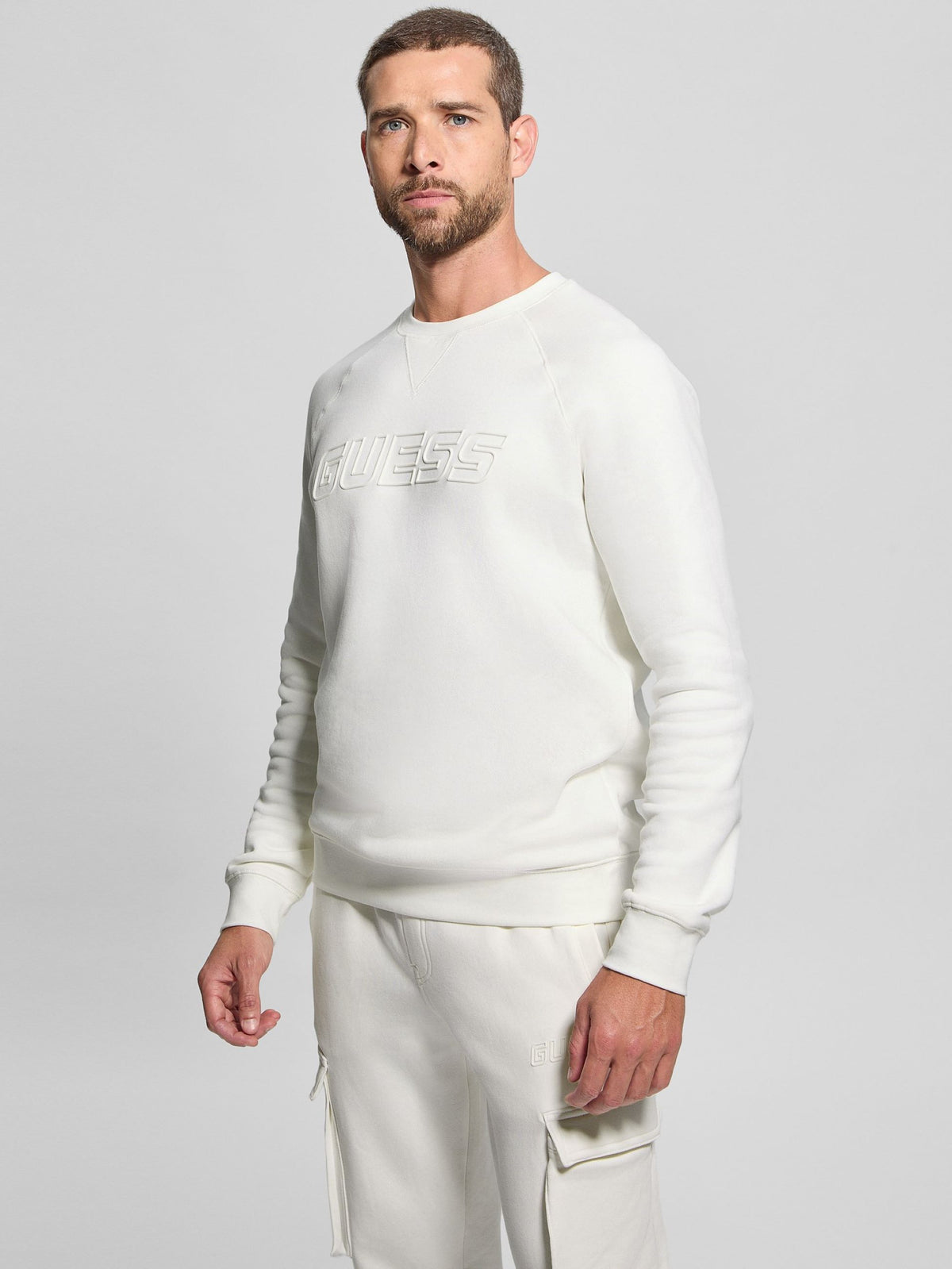 Maglia girocollo con scritta in rilievo Guess, bianco, indossata, vista di tre quarti